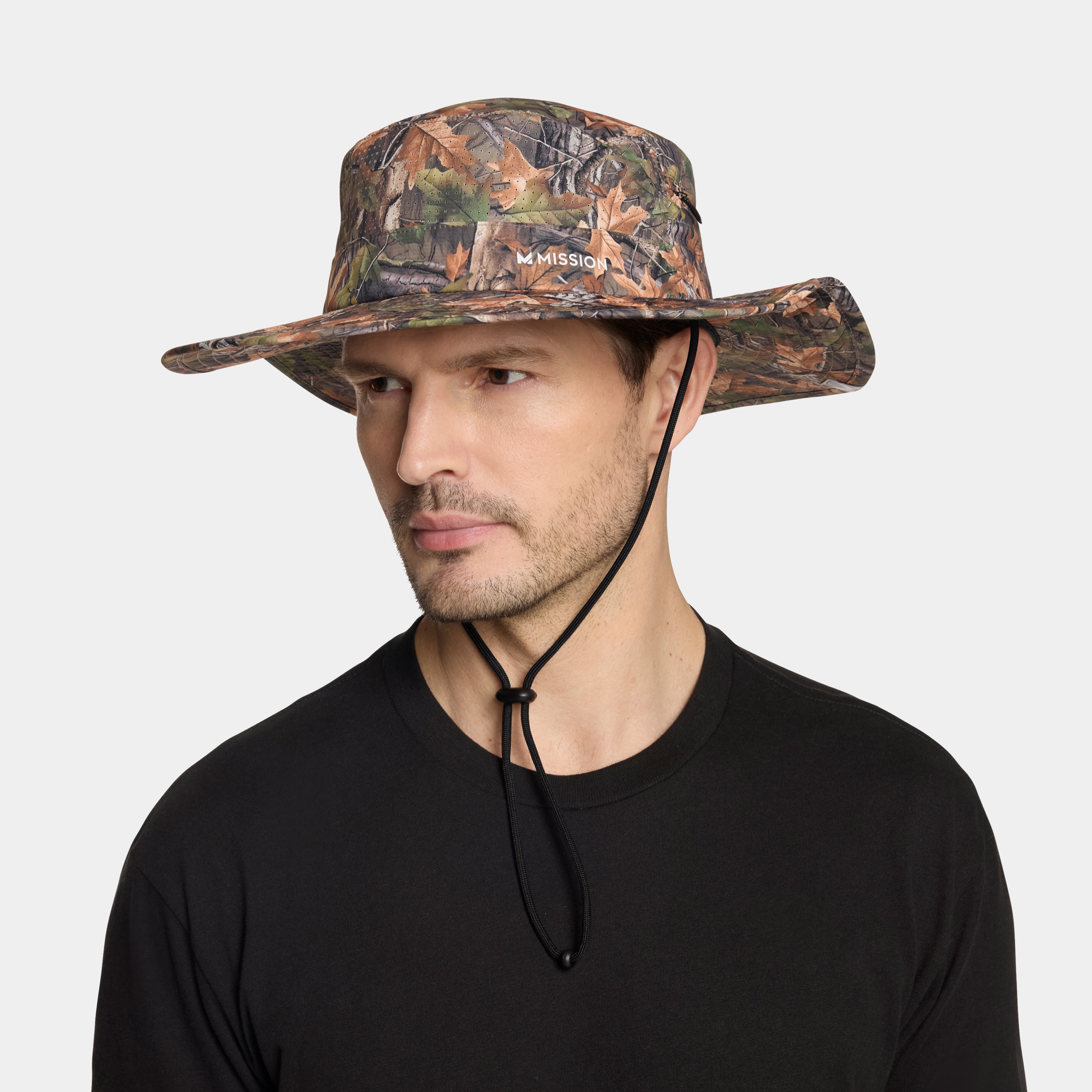Man wearing a camouflage bucket hat with a brand logo on a light gray background