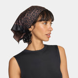 Woman wearing a leopard print headscarf on a plain background