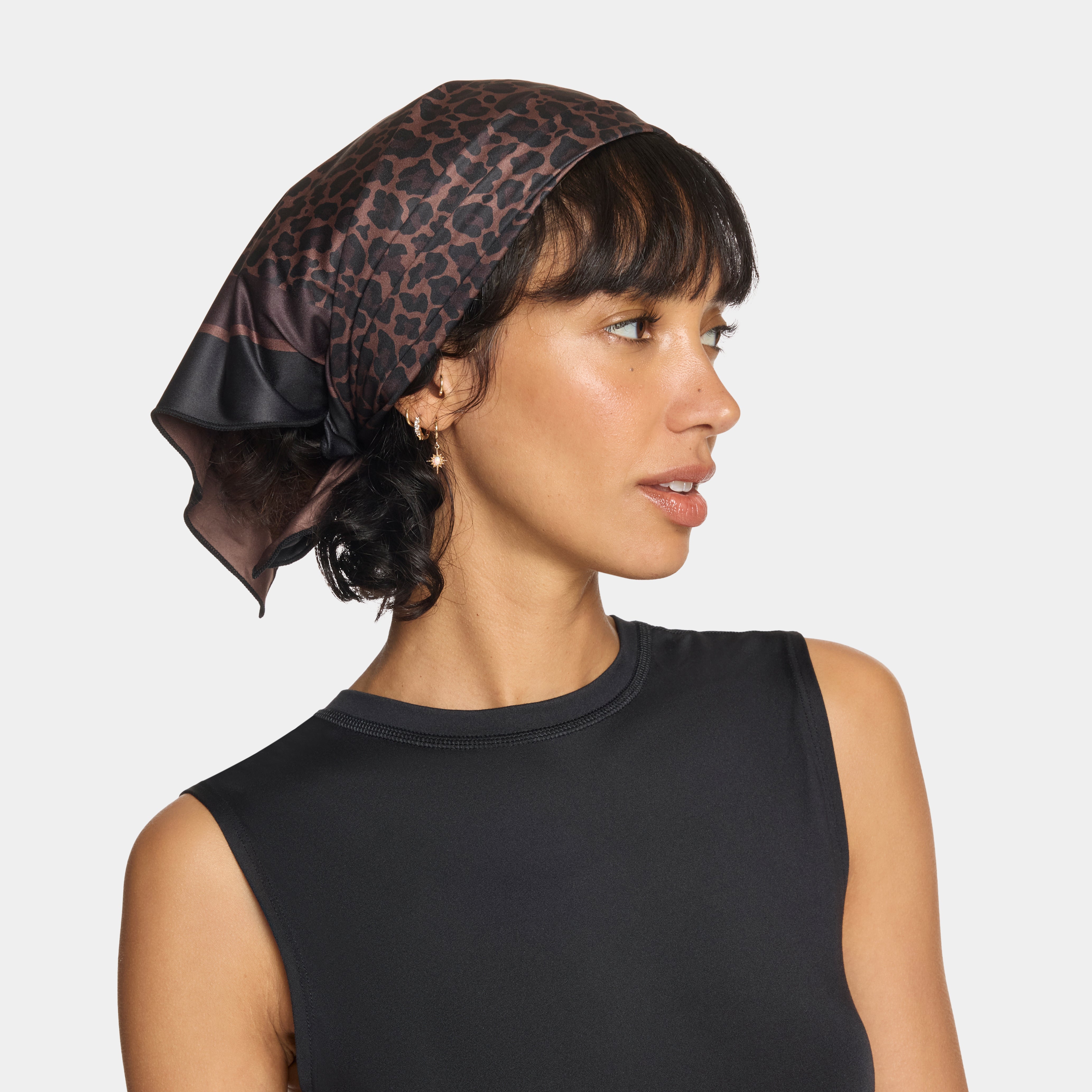 Woman wearing a leopard print headscarf on a plain background