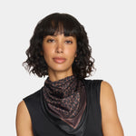 Woman wearing a leopard print scarf against a plain background