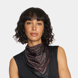 Woman wearing a leopard print scarf against a plain background