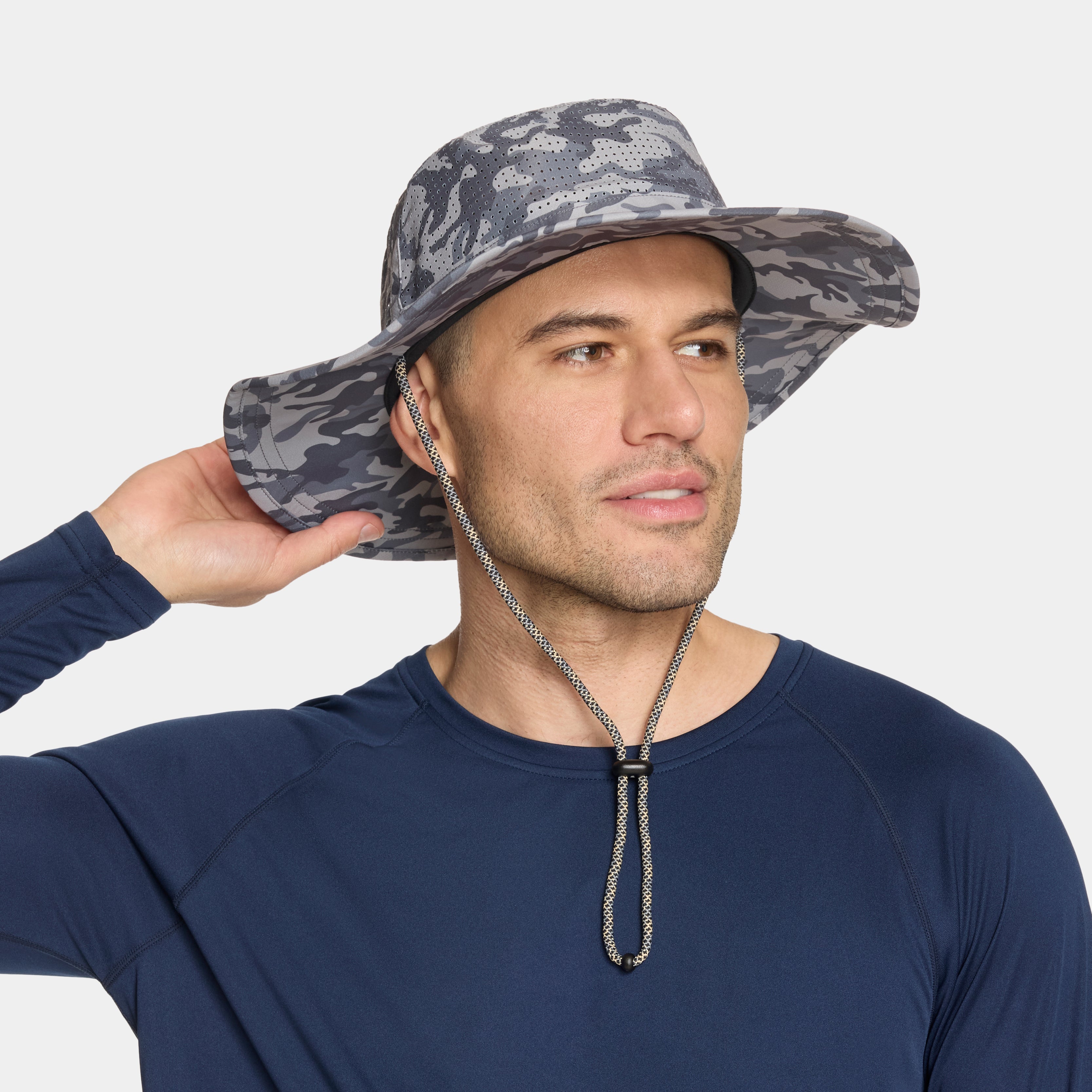 A man wearing a gray and black camouflage wide-brim sun hat with a chin strap, paired with a navy blue long-sleeve shirt, against a light gray background.