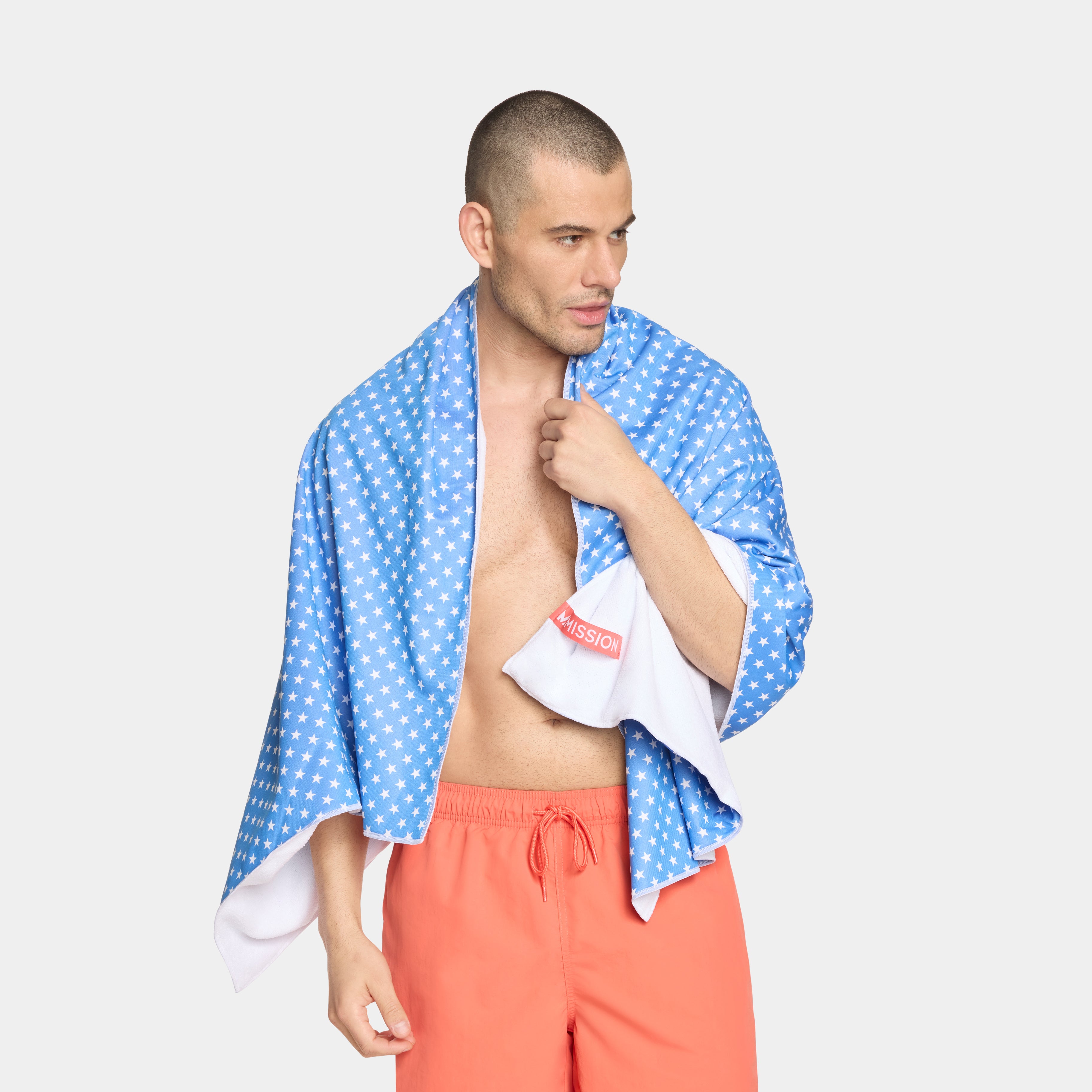 Blue Max Plus Beach Towel with white star pattern and 'Mission' logo on a male model with a white background