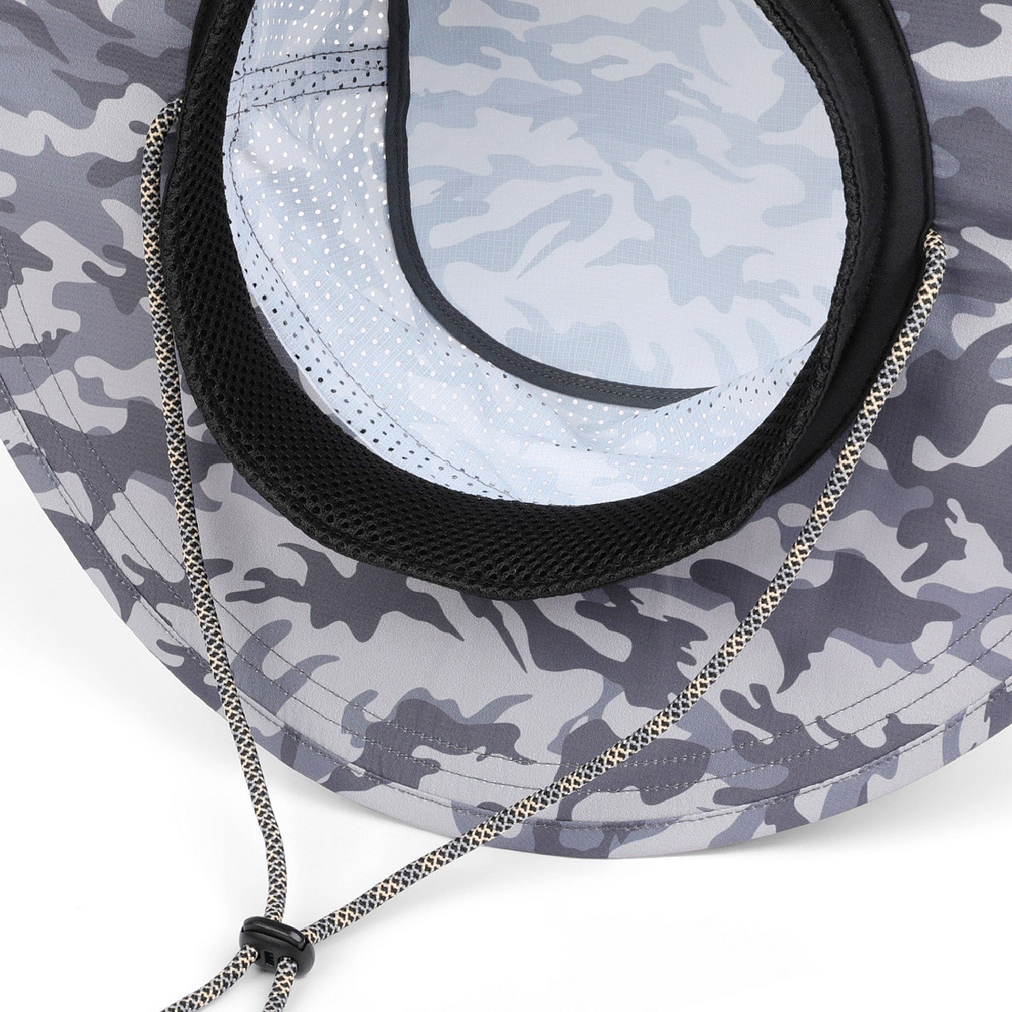 Close-up of a camouflage sun hat with a gray and white camo pattern, black mesh ventilation lining, and a silver drawstring.