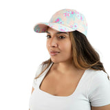 A woman wearing a pastel pink baseball cap with a blue and pink floral pattern, paired with a white scoop-neck t-shirt, photographed against a solid white background.