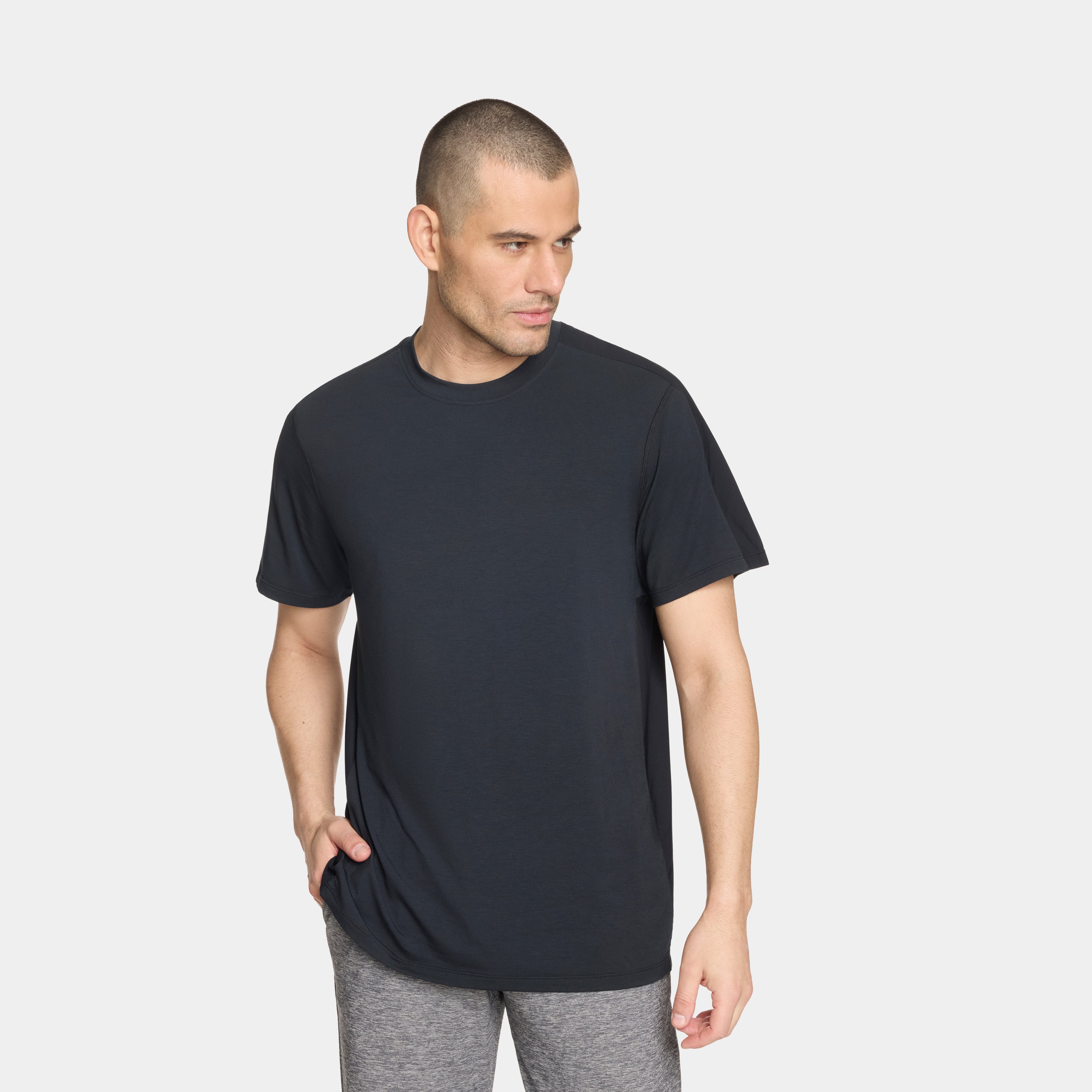 Man wearing a black t-shirt and gray pants on a white background