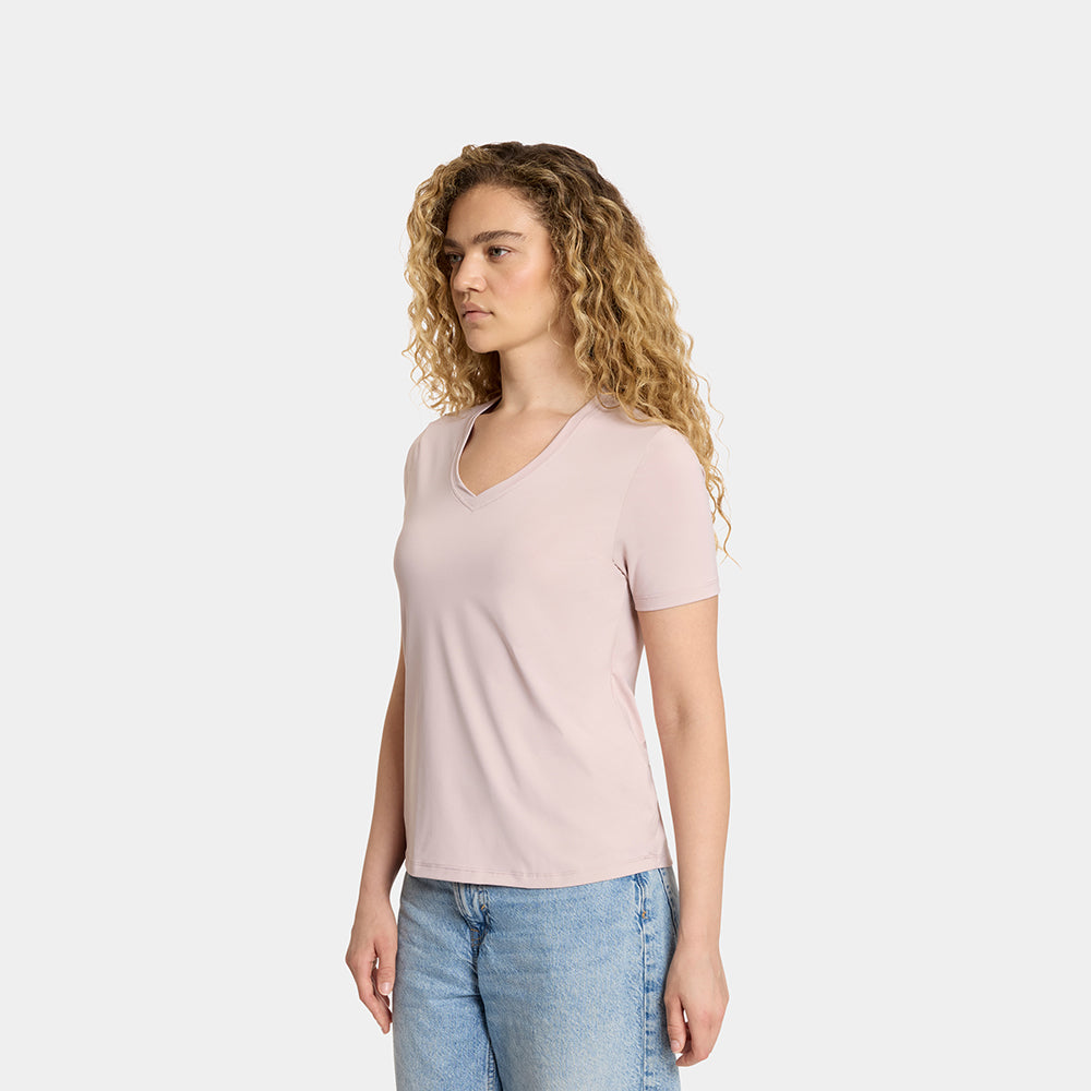 Woman wearing a light pink t-shirt and blue jeans on a white background