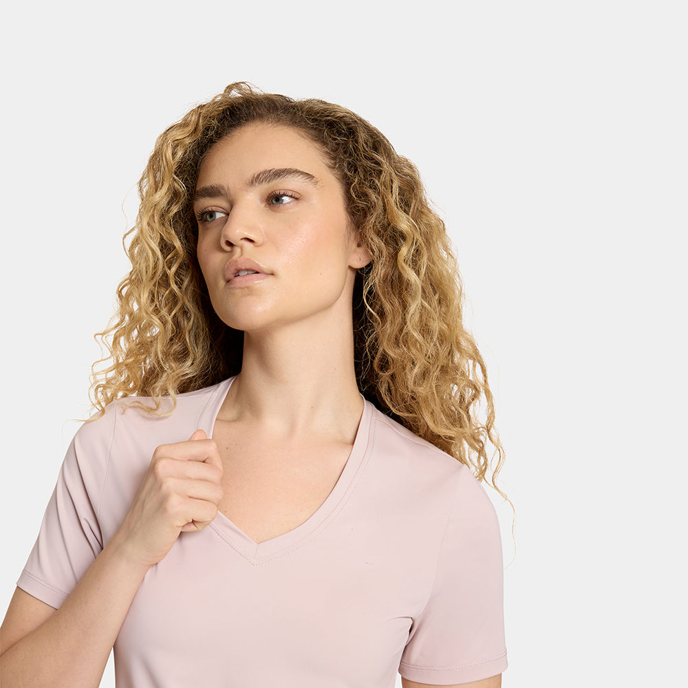 Woman wearing a light pink t-shirt against a plain background