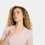 Woman wearing a light pink t-shirt against a plain background