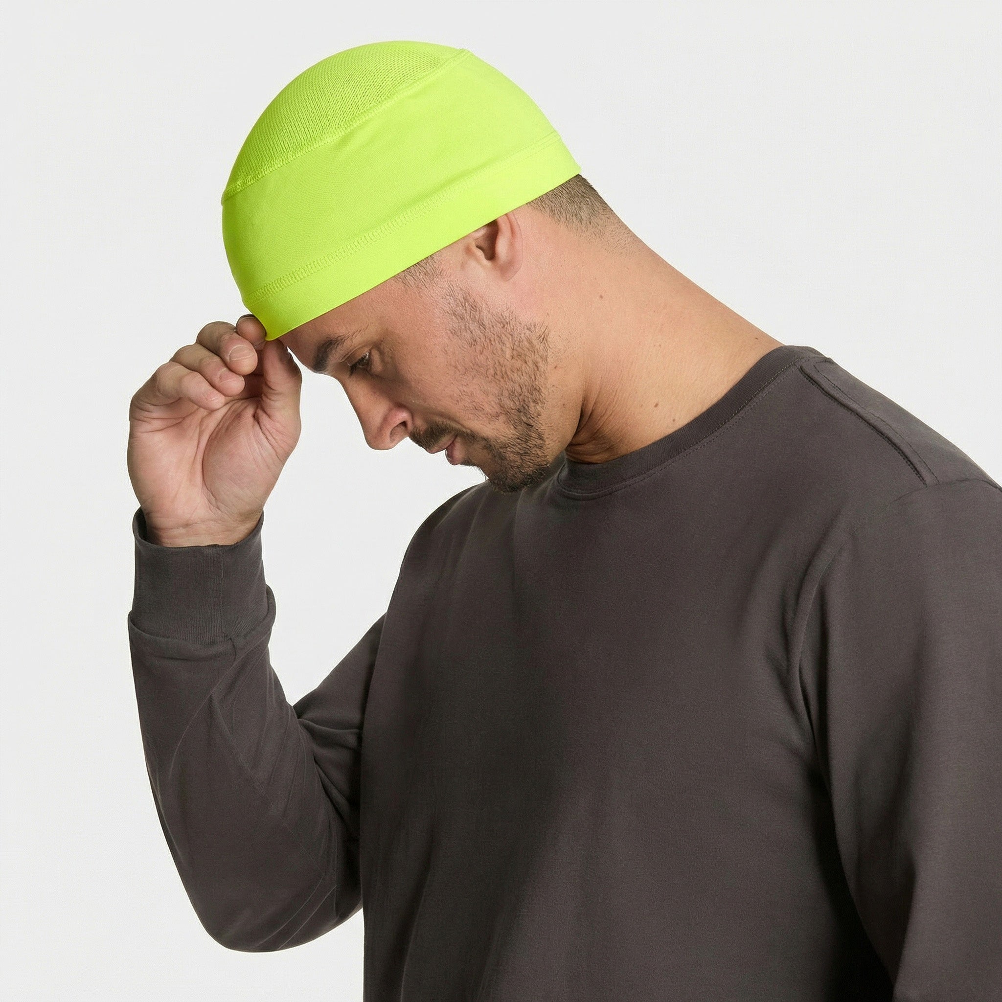 Man wearing a bright green beanie and gray shirt on a white background
